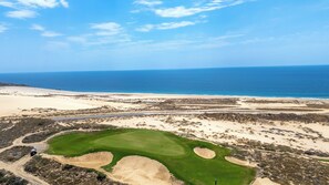 Eine Küstenlandschaft mit Golfplatz, einer Straße und dem Meer.