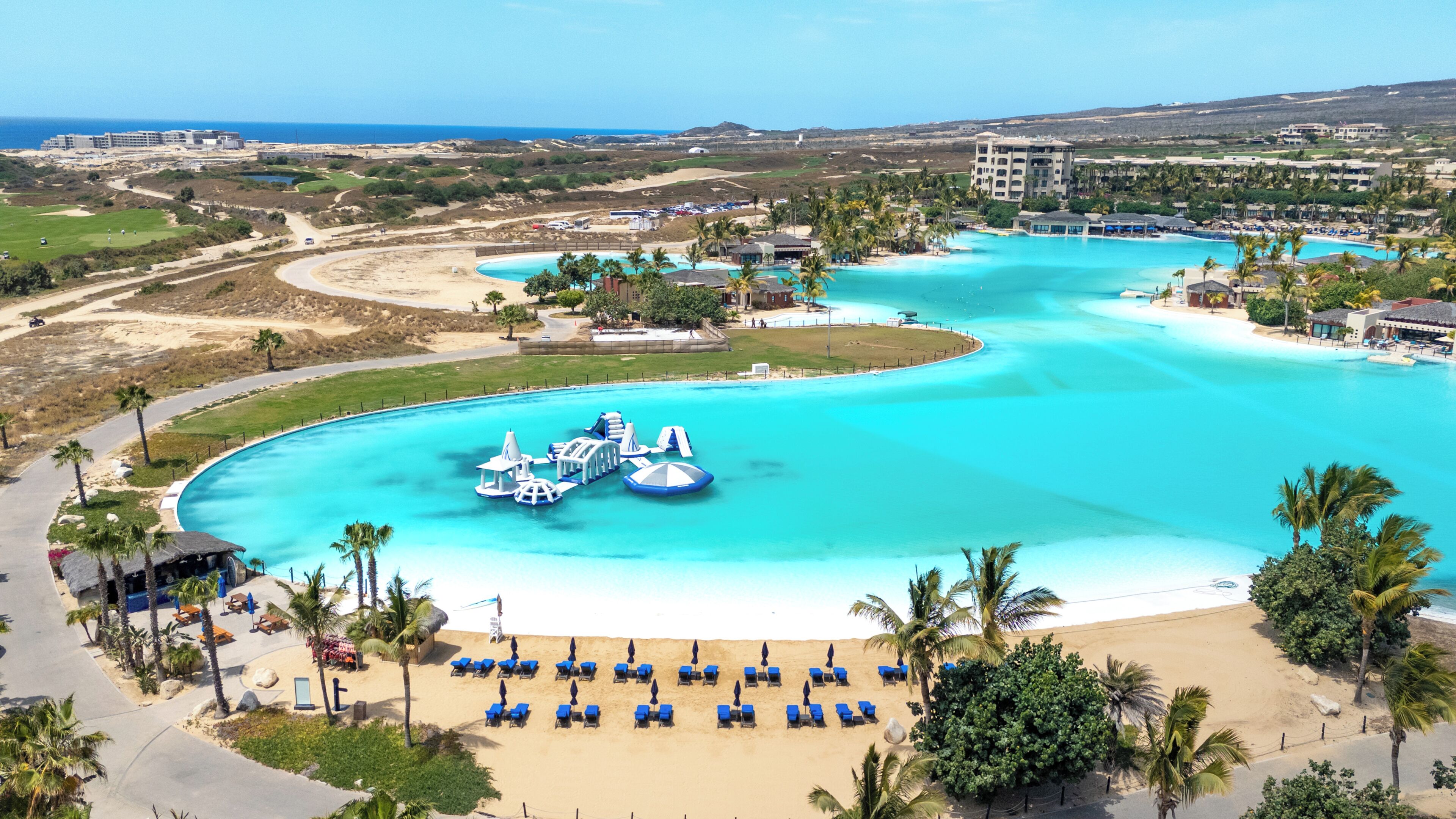 Un complexe hôtelier doté d’une grande piscine, d’une plage et de plusieurs bâtiments.