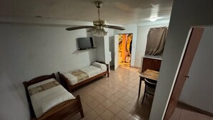 A room with two wooden beds, a ceiling fan, a TV on the wall, and a dining area with a table and chairs. - Borus Hotel (Puerto Iguazú)