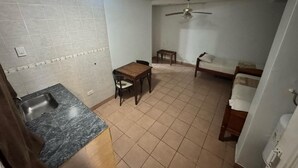 A compact kitchen with a sink, a dining table, and a ceiling fan. - Borus Hotel (Puerto Iguazú)