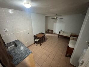 A compact kitchen with a sink, a dining table, and a ceiling fan.