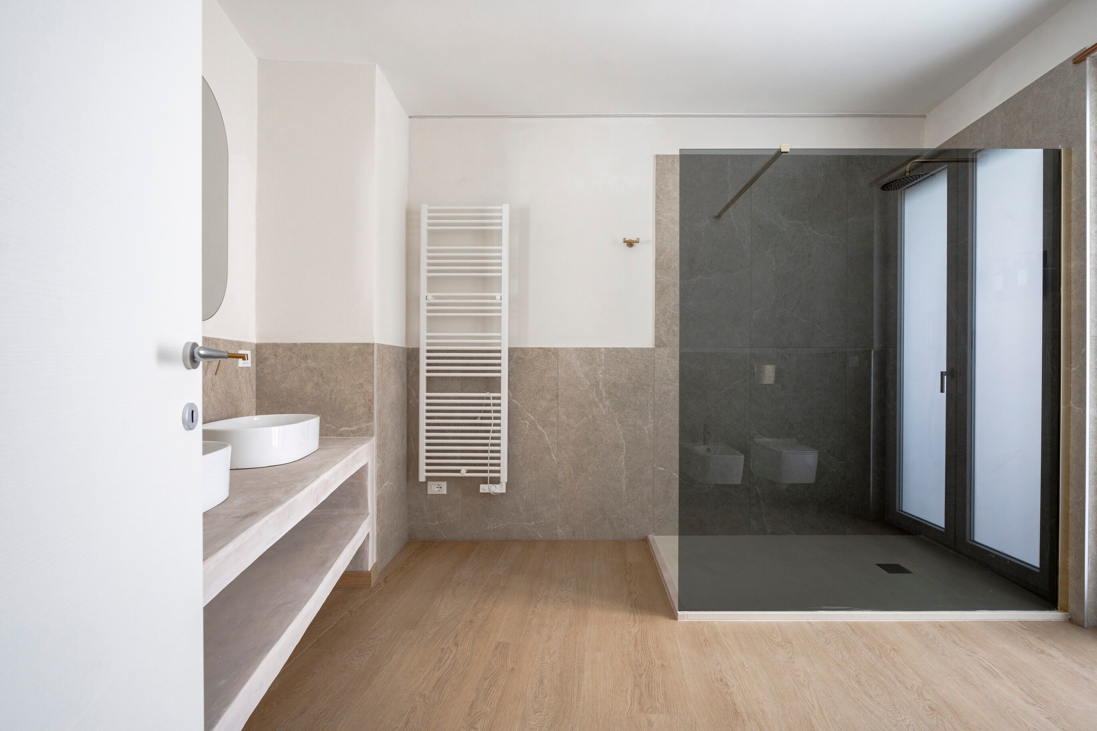 A modern bathroom with a shower, a sink, and a towel rack.
