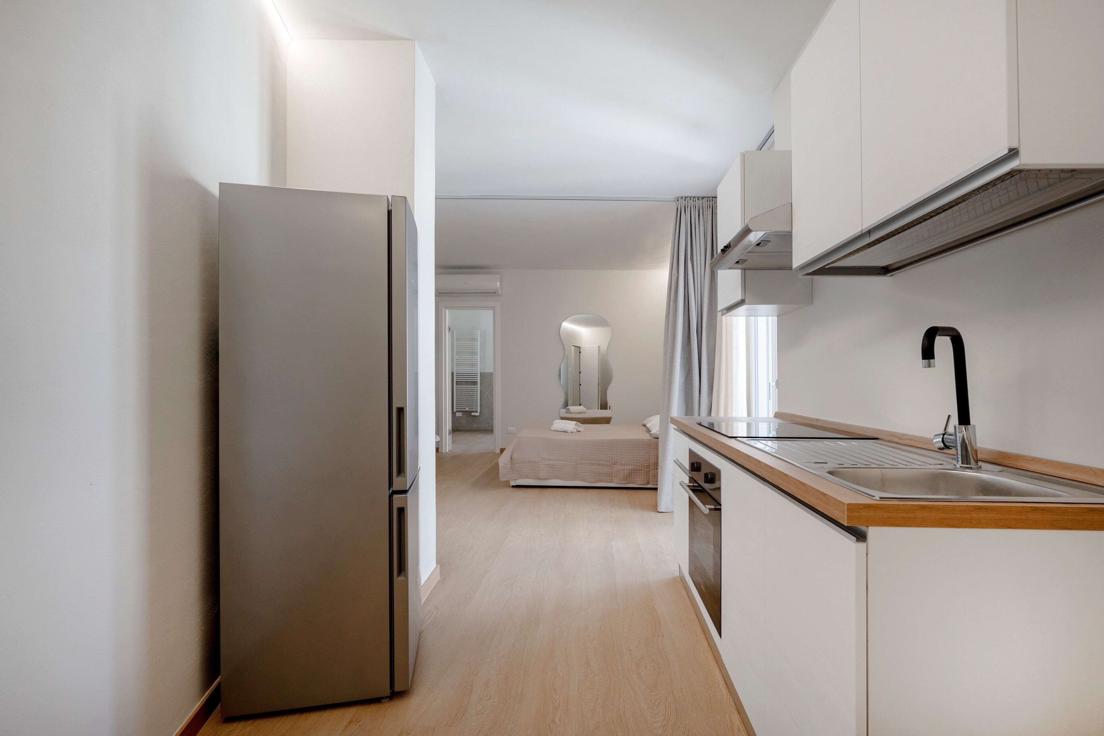 Une cuisine moderne dotée d’un réfrigérateur en acier inoxydable, d’un plan de travail en bois et d’un évier.
