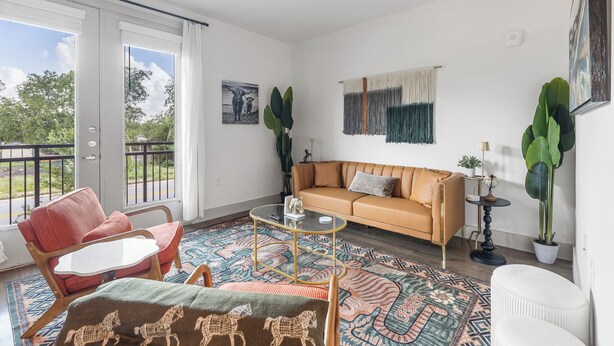 Ein Wohnzimmer mit einer Couch, Sesseln, einem Couchtisch und einem großen Fenster mit Blick.