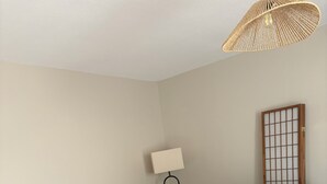 Ein Essbereich mit einem runden Holztisch, gepolsterten Stühlen, einer Stehlampe und einer Couch mit Kissen.