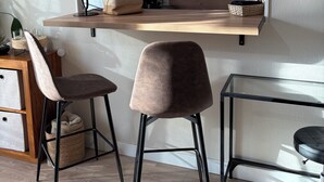 Eine moderne Küche mit einer Holzausziehtheke, zwei Barhocker und einem integrierten Fernseher.