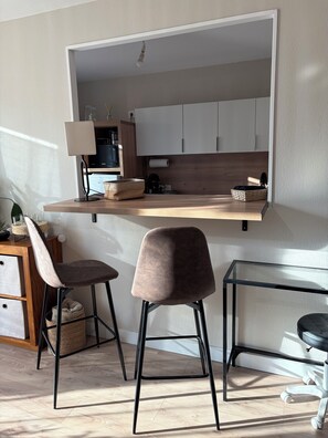 Eine moderne Küche mit einer Holzausziehtheke, zwei Barhocker und einem integrierten Fernseher.