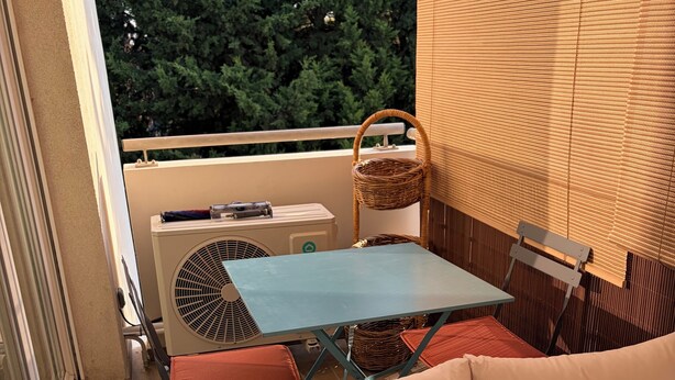Ein Balkon mit Tisch, Stühlen und einem Korbwäscheschrank.
