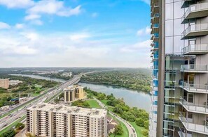 A high-rise building with multiple balconies overlooking a river and a highway. - Downtown Skyline & Lake Views l Rooftop Pool (Austin)