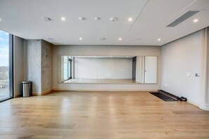A spacious room with a large mirror, wooden flooring, and a view through the window. - Downtown Skyline & Lake Views l Rooftop Pool (Austin)