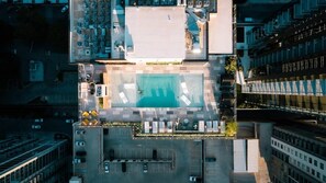 Vista aérea de uma área de piscina no terraço, com uma piscina retangular, cercada por espreguiçadeiras e um pequeno jardim.