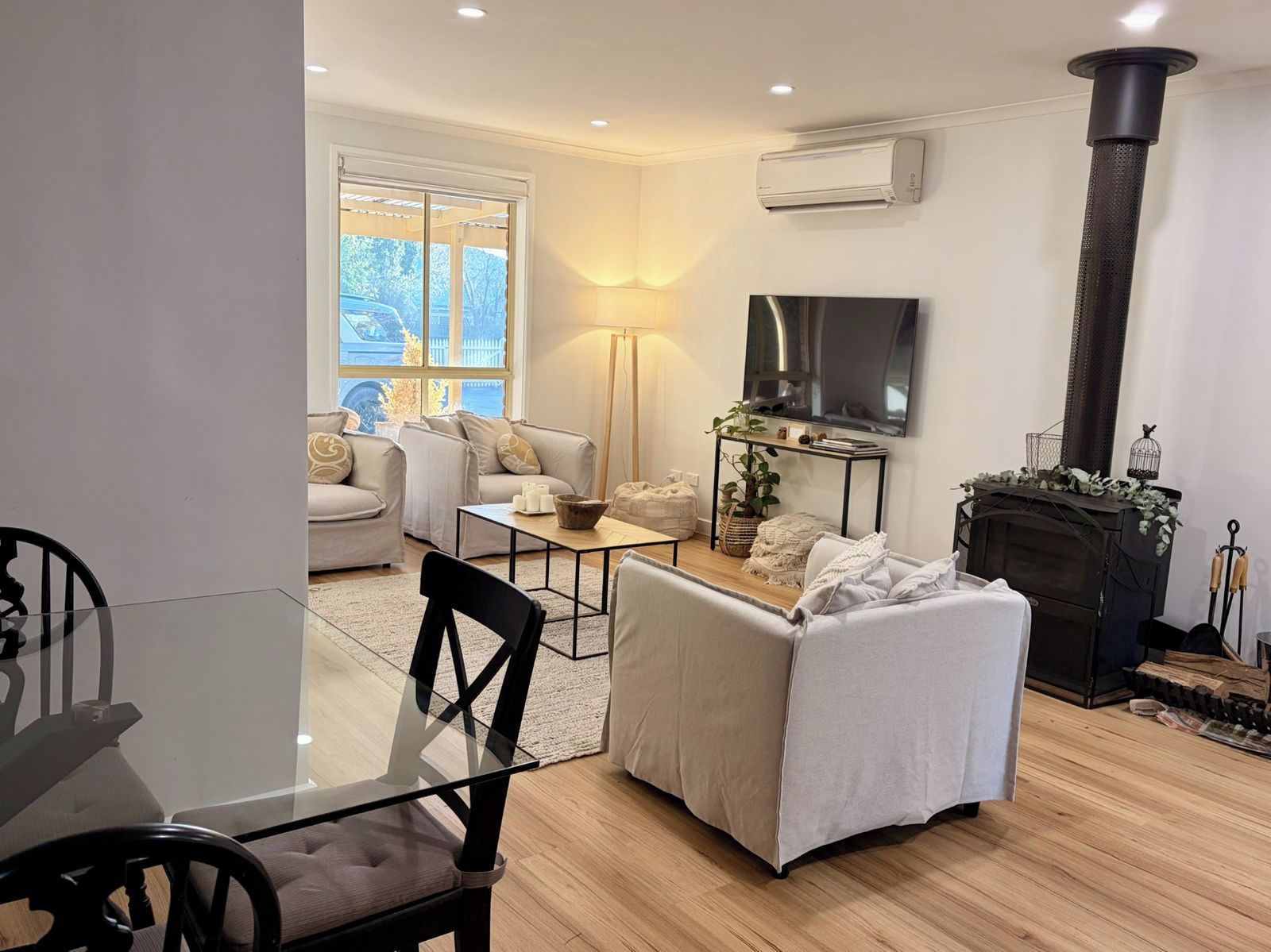 A modern living room with a sofa, a glass coffee table, a TV, and a fireplace.
