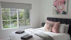 Une chambre à coucher avec un lit, un ventilateur de plafond, une fenêtre donnant sur un beau paysage et un tableau accroché au mur.