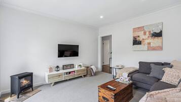 A modern living room with a fireplace, a flat-screen TV, a grey sofa, and a wooden coffee table.