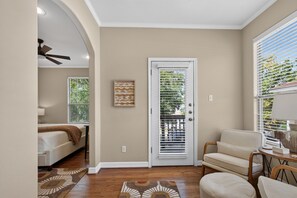 A room with a bed, a chair, a door with blinds, and a ceiling fan. - 6BR Central AUS w/ Fenced Yard + Pets, Fire pit! (Austin)