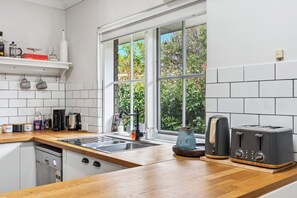 Una cocina moderna con encimera de madera, un lavamanos, una cafetera y dos tostadoras.
