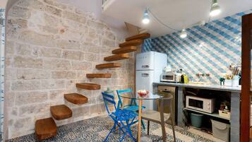 A kitchen with a stone wall, wooden steps, a blue chair, and a microwave.