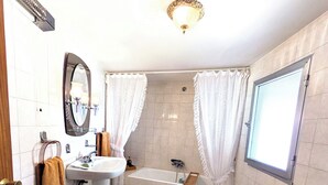 Casa de banho com lavatório, espelho, sanita, bidé e banheira.