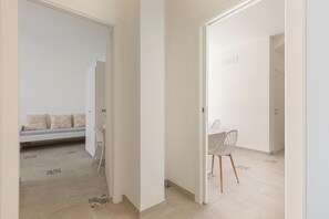 A hallway with a sofa and a chair, leading to a room with a bed. - B&B Li Peticurti | Camera tripla (Santa Cesarea Terme)