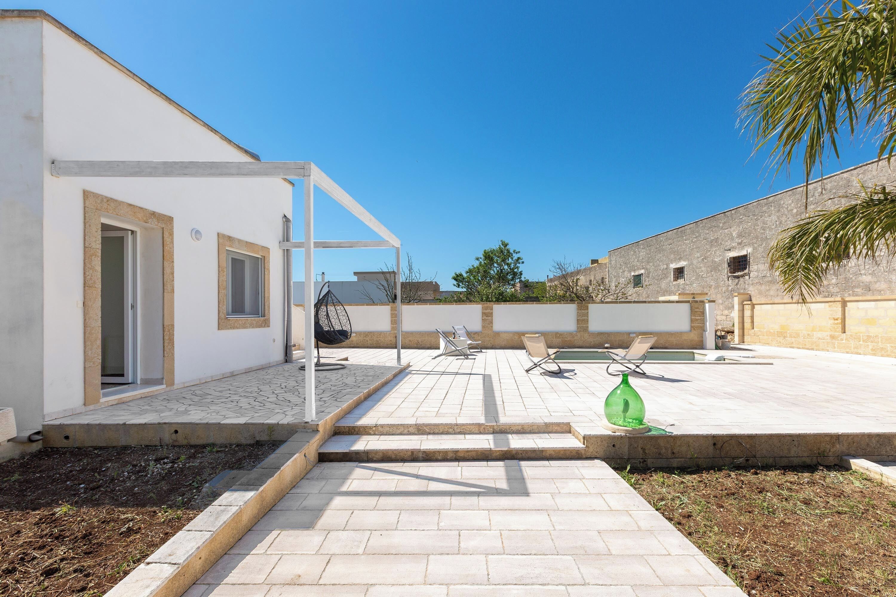 Eine moderne Außenpatio mit Pool, Sitzbereich und einem weißen Gebäude mit einer Pergola.