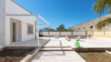 Eine moderne Außenpatio mit Pool, Sitzbereich und einem weißen Gebäude mit einer Pergola.