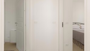 A narrow hallway leading to a room with a bed, a radiator, and a door. - B&B Li Peticurti | Camera tripla (Santa Cesarea Terme)