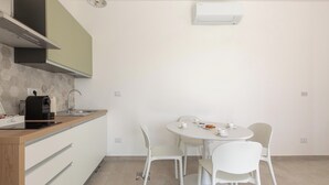 Uma cozinha compacta com área de jantar, incluindo cafeteira, pia e mesa com cadeiras.