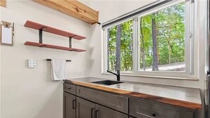 Una cucina con finestra, piano di lavoro in legno e pensili in metallo.