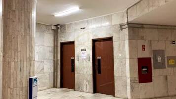 Um corredor com paredes de mármore e duas portas de madeira, uma das quais tem uma placa em cima.