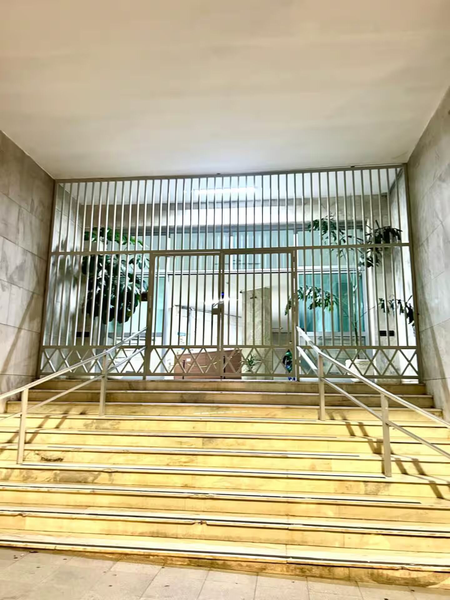 A staircase with metal railings leading to a glass door.