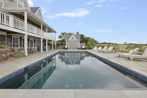 A swimming pool with lounge chairs and a covered patio area.