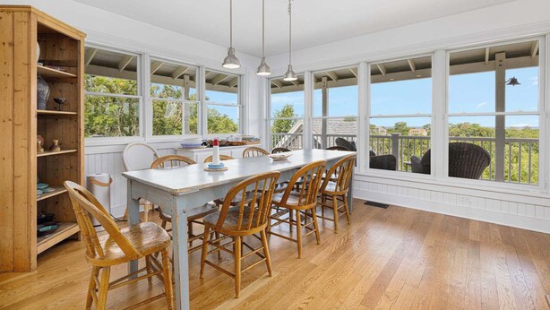 A spacious kitchen with a large island, wooden chairs, and a view of the outdoors.