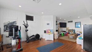 A home gym with exercise equipment, a television, and a children's play area.