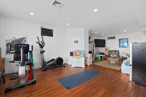 A home gym with exercise equipment, a television, and a children's play area.