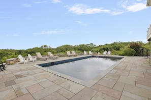 A swimming pool with lounge chairs and a stone patio.