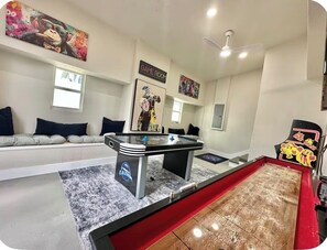 A room with a foosball table, a sofa, and a gaming chair. - Waterfront Escape! 4 bed/2.5 bath cozy-chic getaway (Tampa)