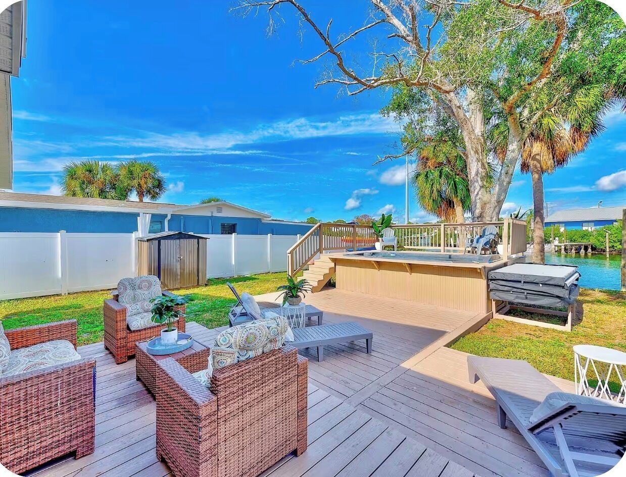 Una terraza con mobiliario de mimbre, zona de barbacoa y una piscina al fondo.