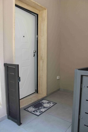 A closed door with a doorknob, a metal mail slot, and a doormat with a floral design. - Azzurra's Cozy Home—Perfect for hosting families and groups of friends (Galatina)