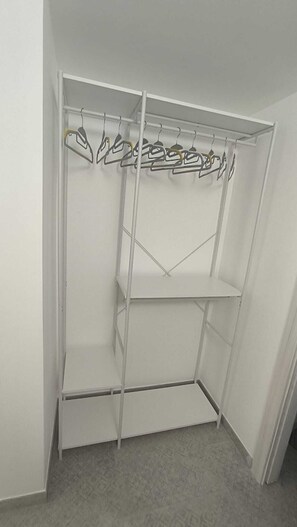 A white closet with three shelves and a hanging rod. - Azzurra's Cozy Home—Perfect for hosting families and groups of friends (Galatina)