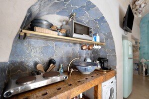 Una cucina con schienale in pietra, piano di lavoro in legno, fornello, lavello e lavatrice.