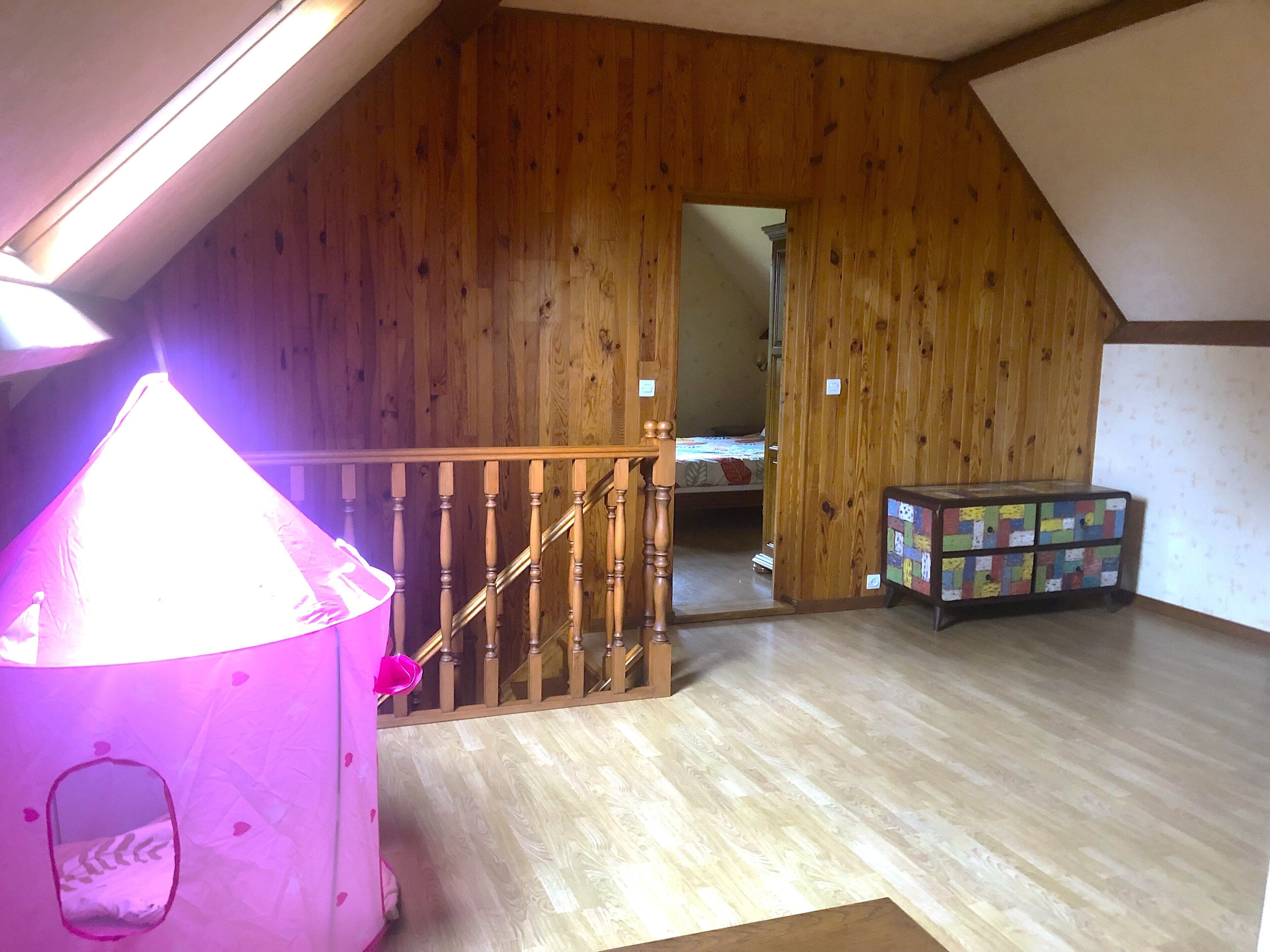 A room with wooden walls, a staircase, a bed, and a colorful storage unit.