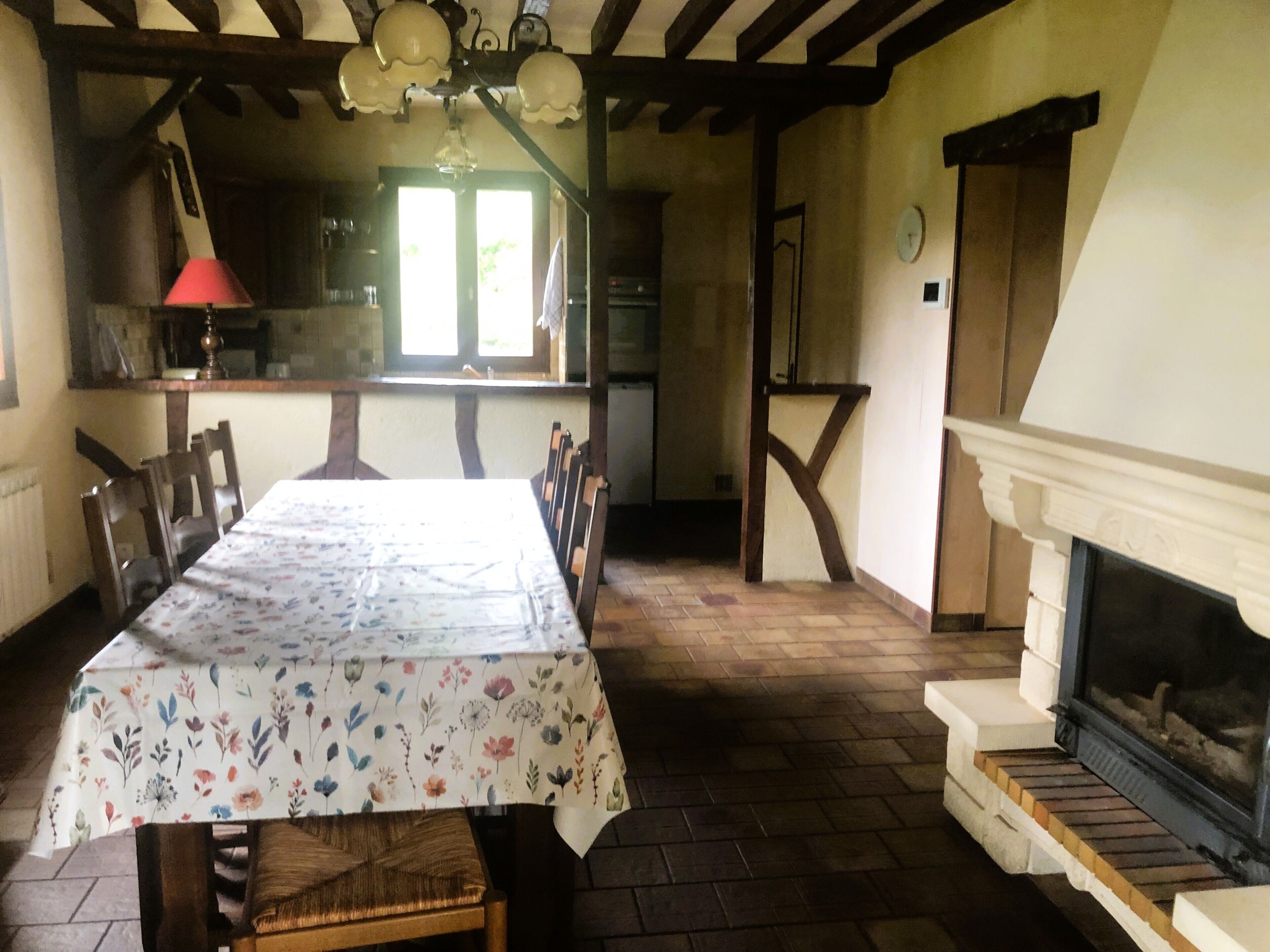 A dining room with a table set for six, wooden chairs, a fireplace, and a kitchen in the background.
