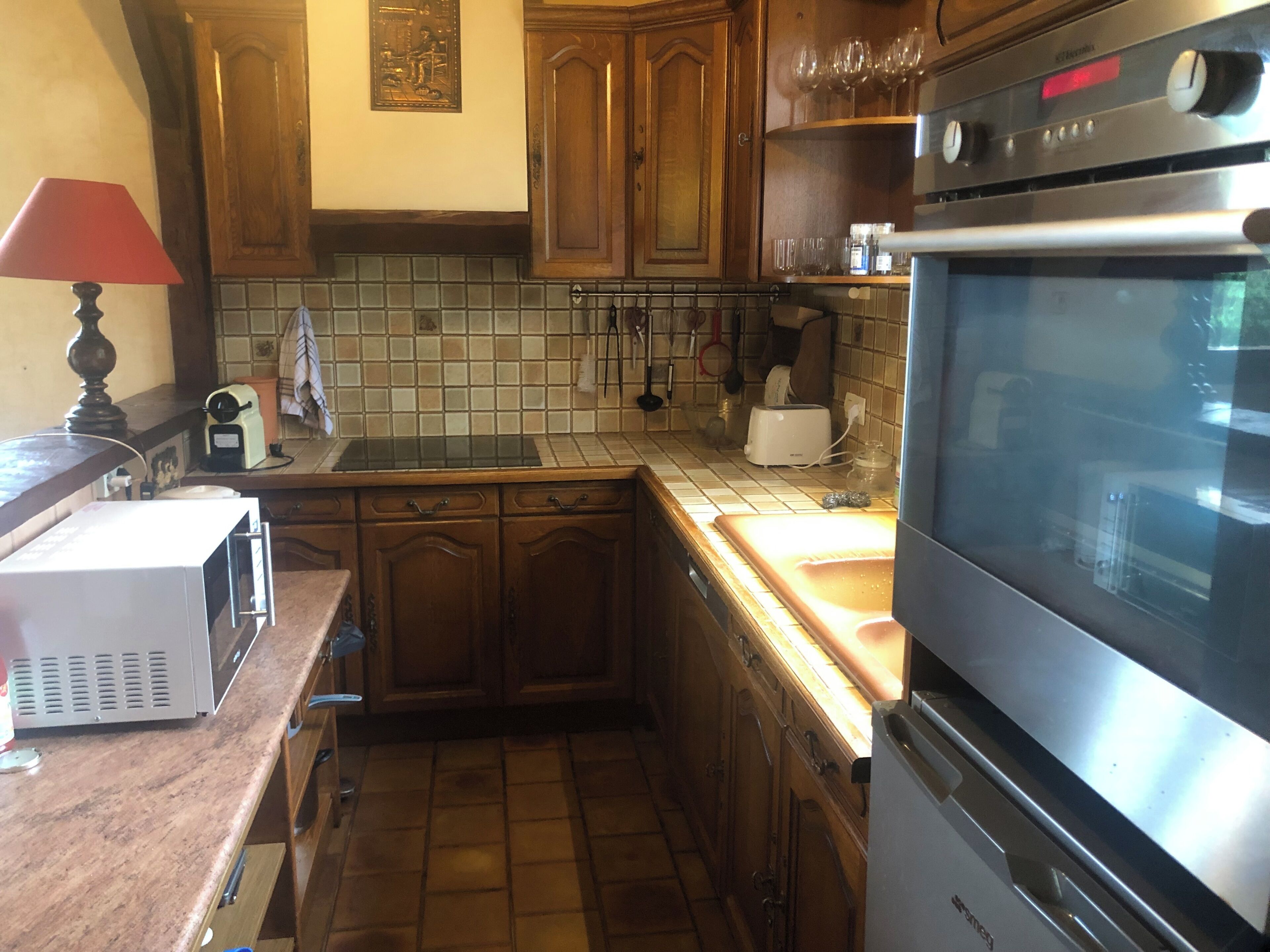A compact kitchen with wooden cabinets, a microwave, a toaster, and a stove.