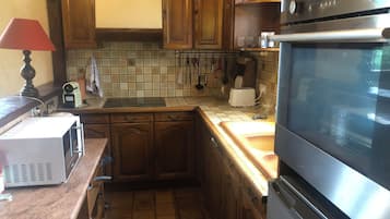 A compact kitchen with wooden cabinets, a microwave, a toaster, and a stove.