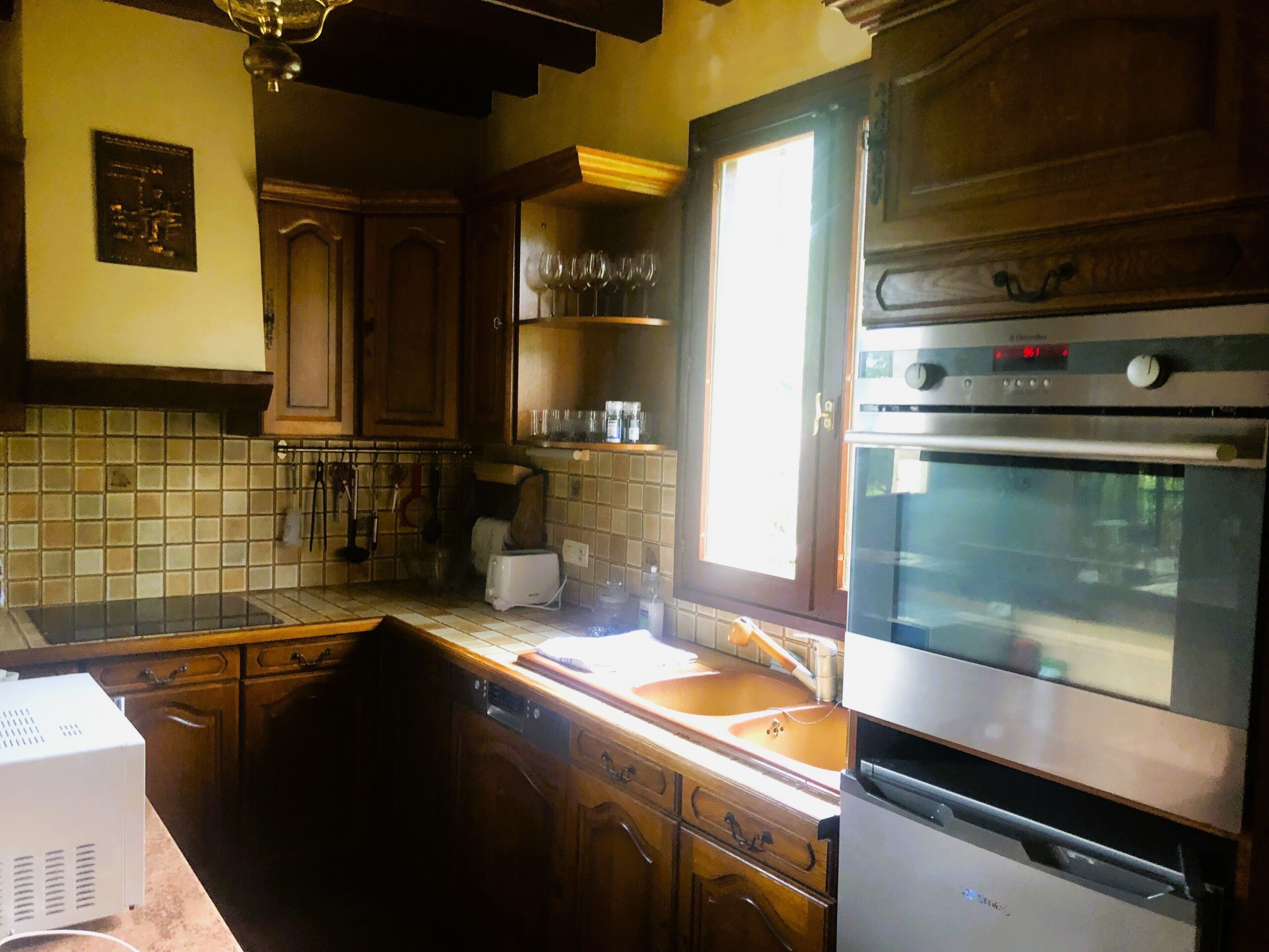 A kitchen with wooden cabinets, a stainless steel oven, and a window.