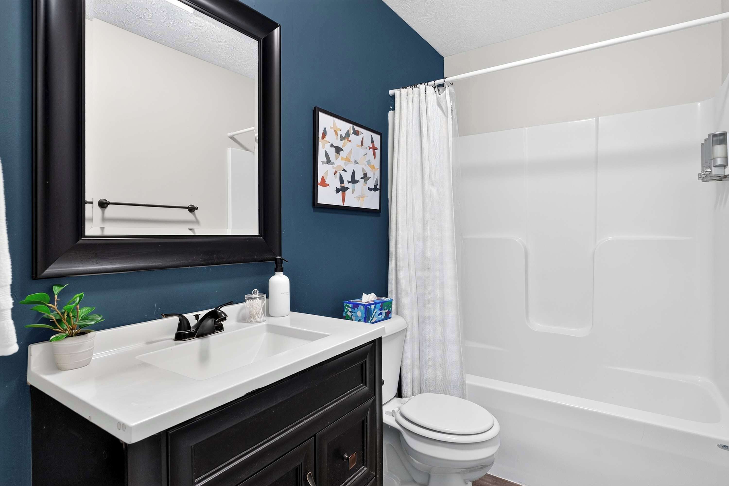 A bathroom with a white sink, a black cabinet, a toilet, and a bathtub.