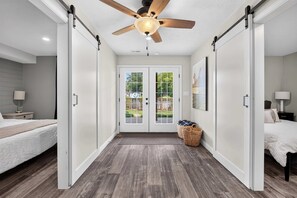 A hallway with a ceiling fan, a double door with glass panels, and a view of the outdoors.