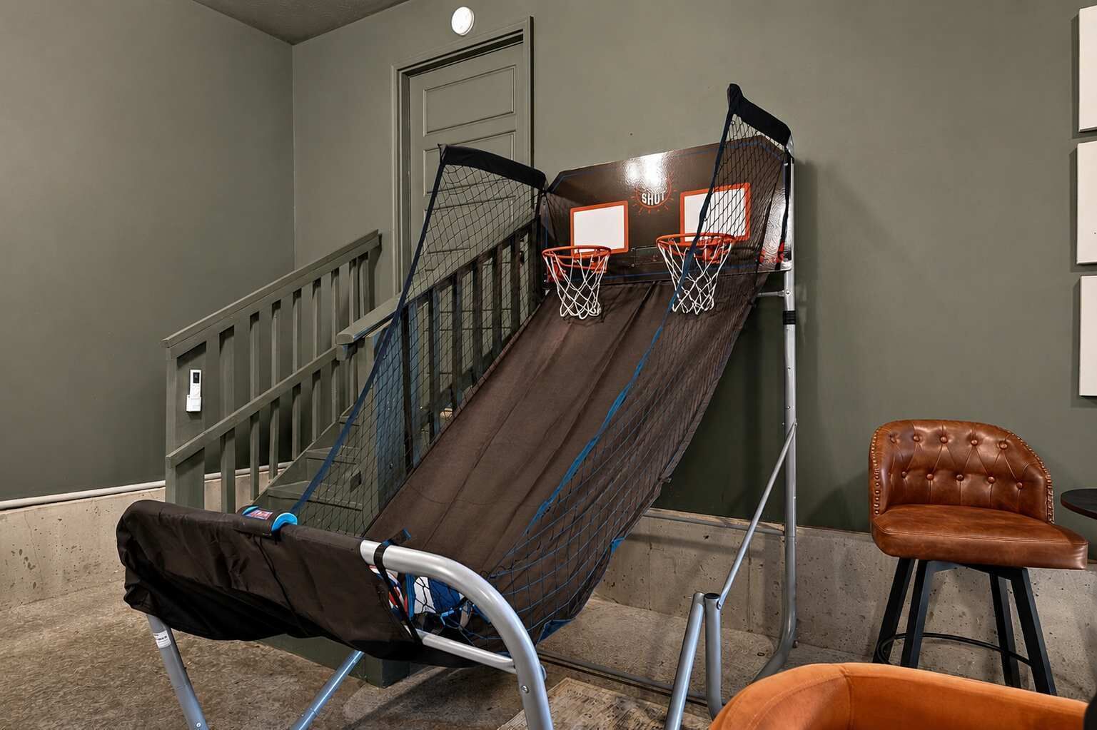 Een basketbalveldje tegen een muur, met een stoel en een bank in de buurt.