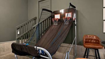 Een basketbalveldje tegen een muur, met een stoel en een bank in de buurt.