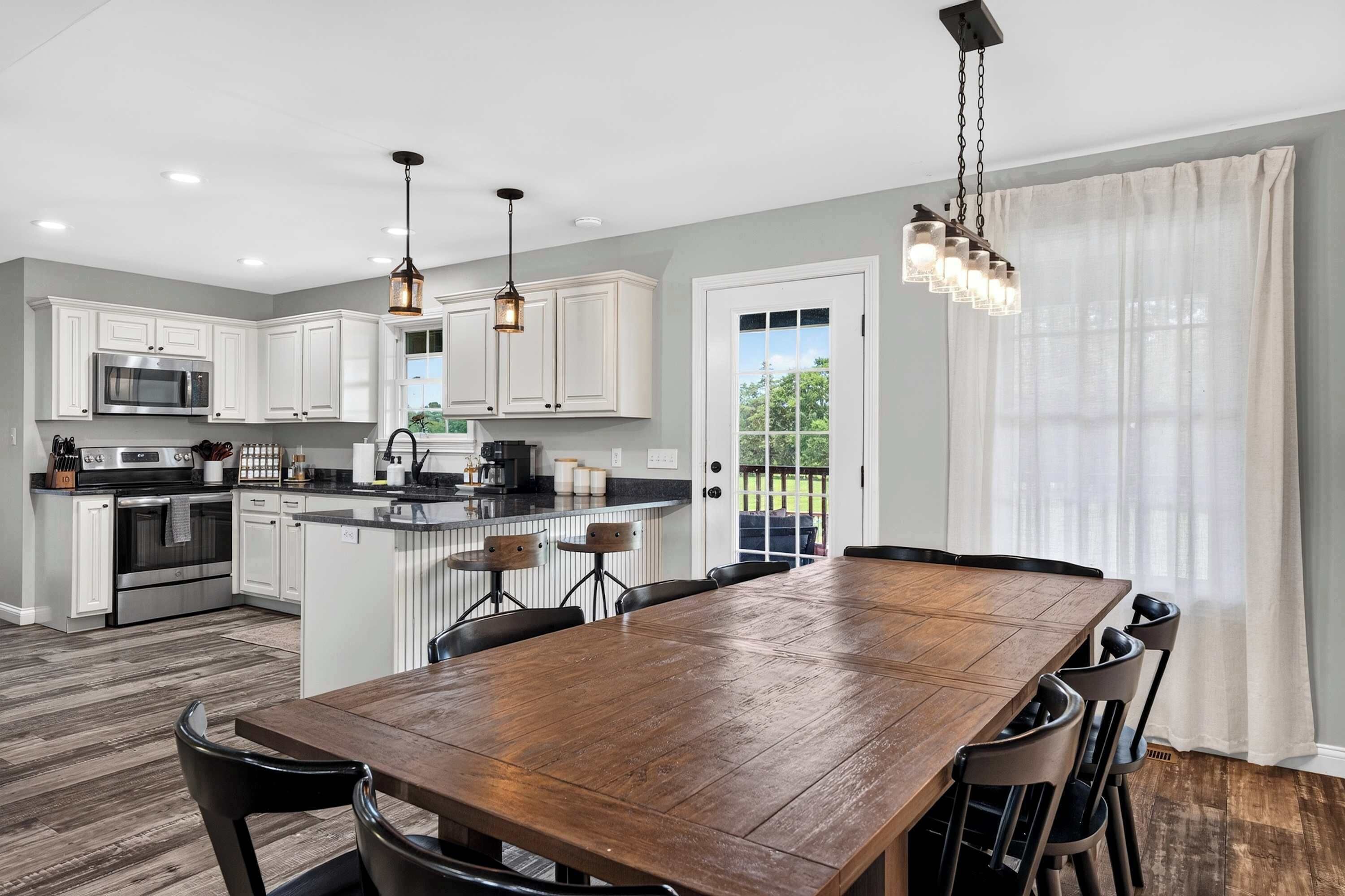 Una cocina moderna con armarios blancos, electrodomésticos de acero inoxidable y una mesa de comedor de madera con sillas.